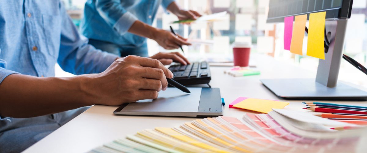 designer graphic creative creativity working together coloring using graphics tablet and a stylus at desk with colleague